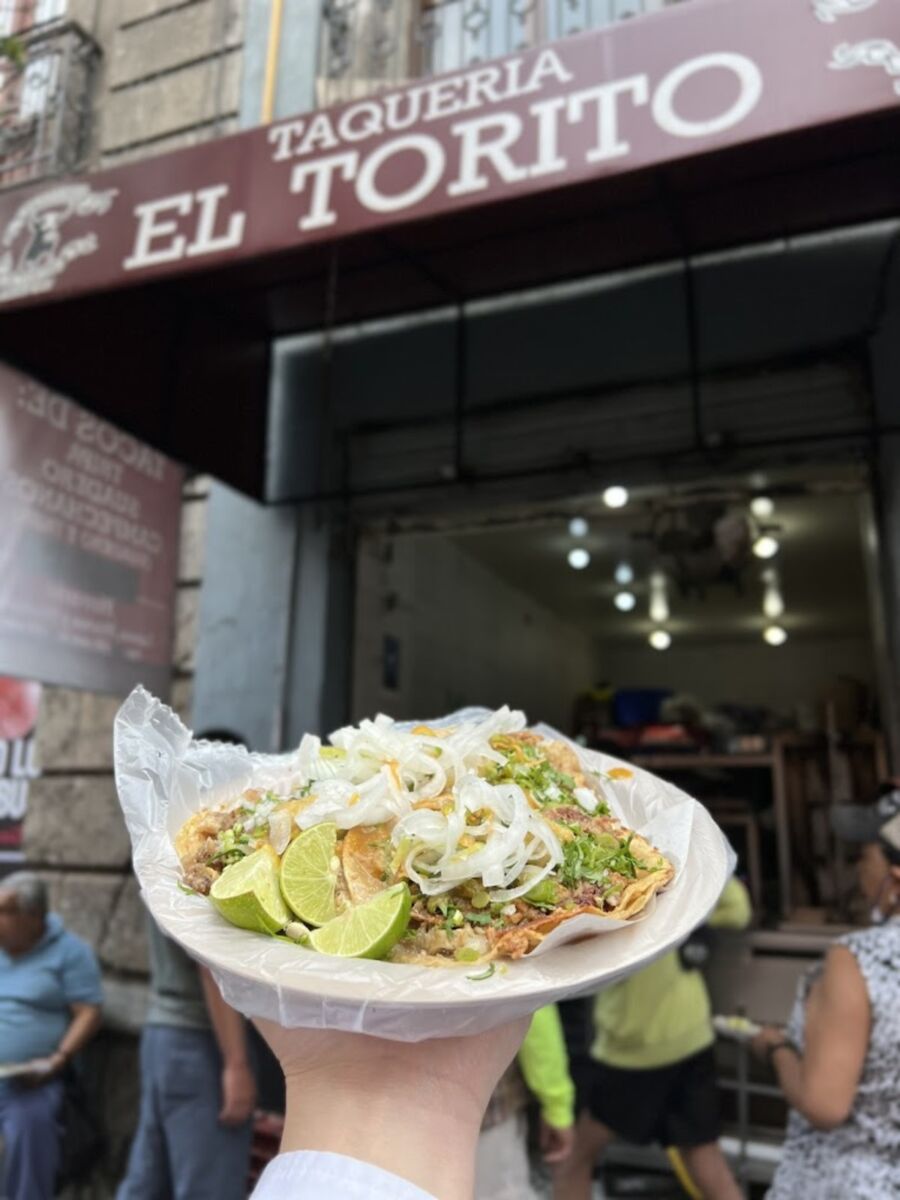 persona enseñando tacos frente a la Taquería El Torito