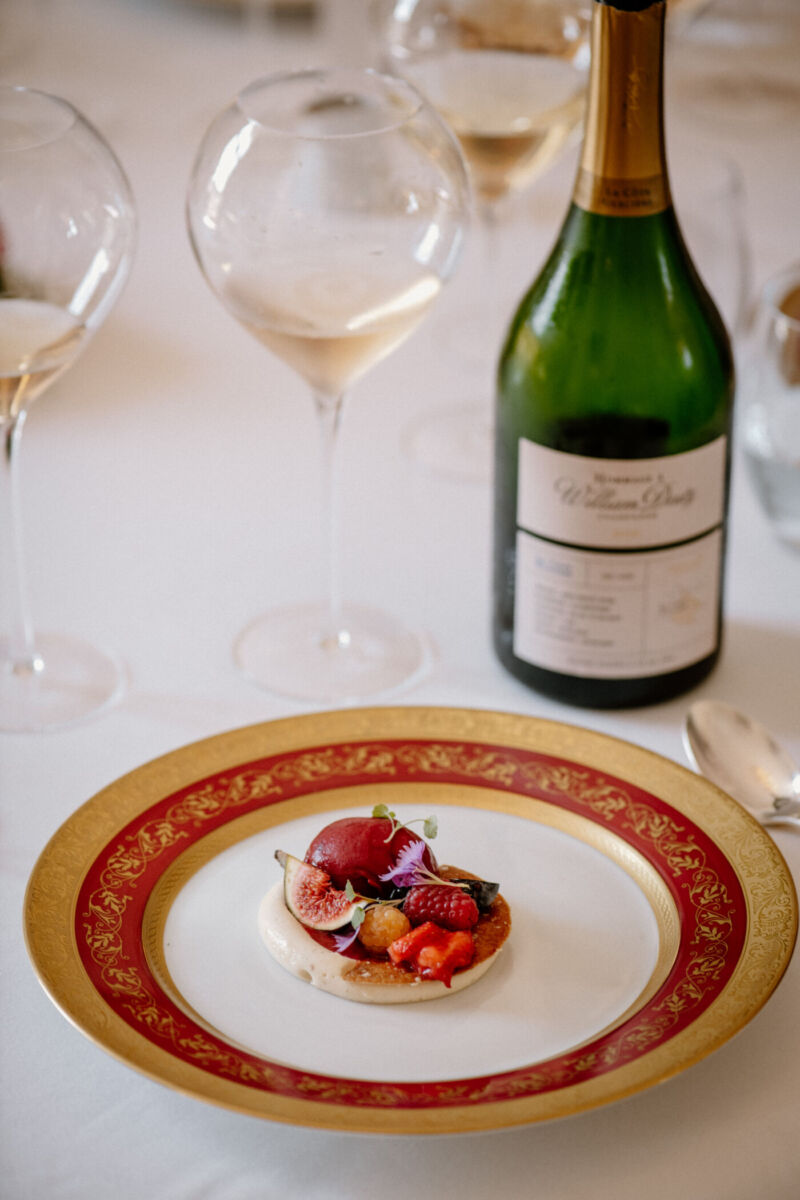 plato de alta cocina con una botella de champaña de fondo