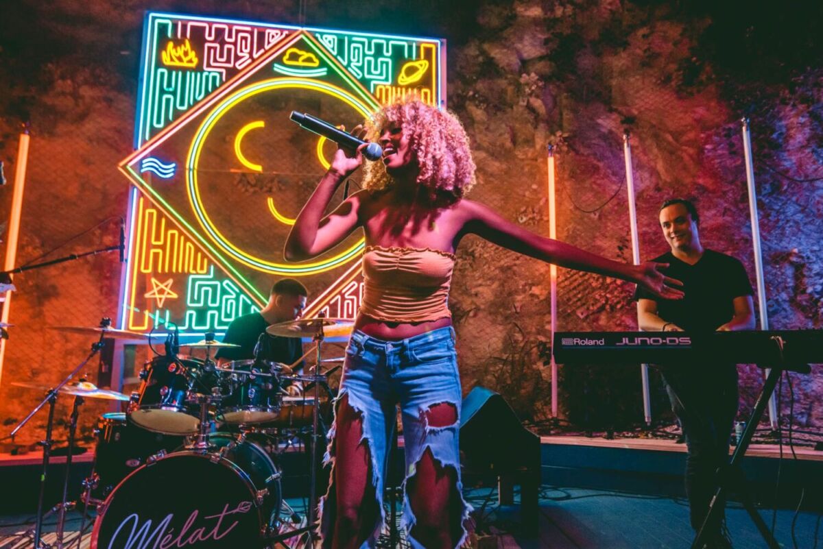 mujer de pelo rosa cantando con luces neón
