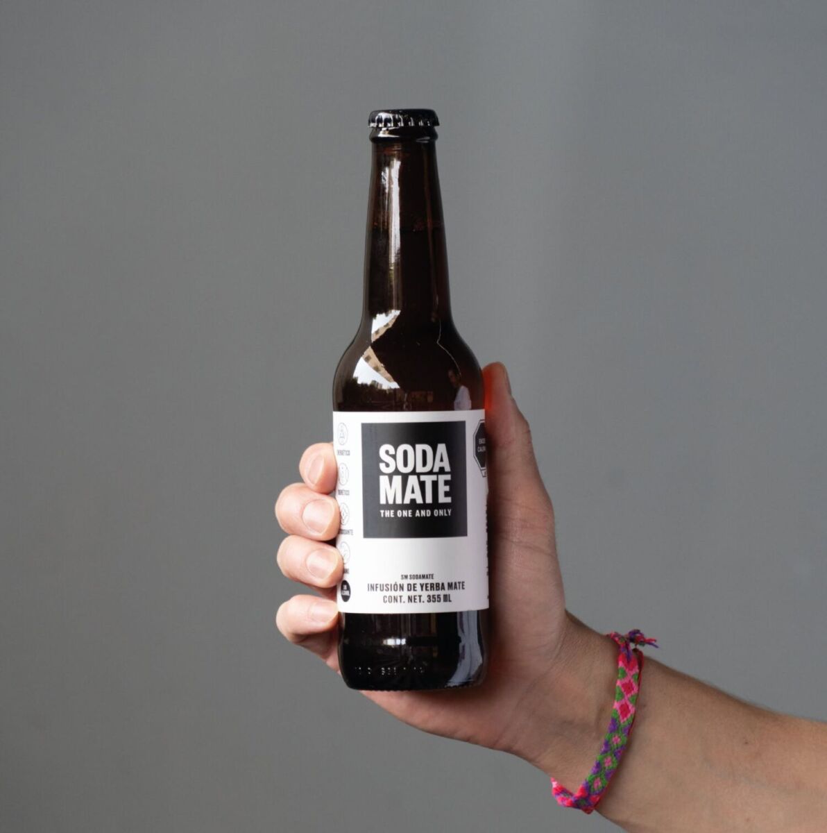 mano sosteniendo una botella de soda mate