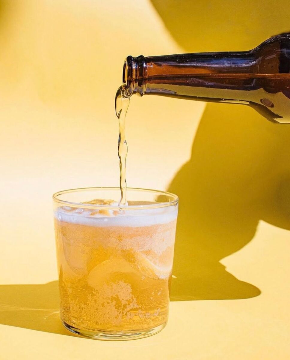 botella sirviendo soda de yerba mate en un vaso de cristal