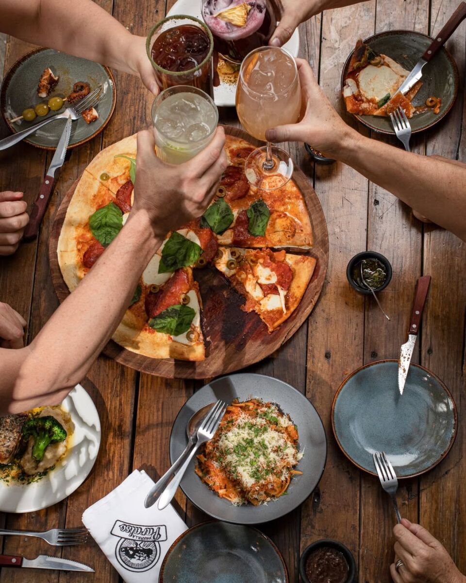 personas brindando en restaurante cerca de estadio azteca con pizza