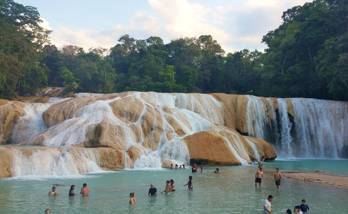 personas nadando en una cascada de agua turquesa 