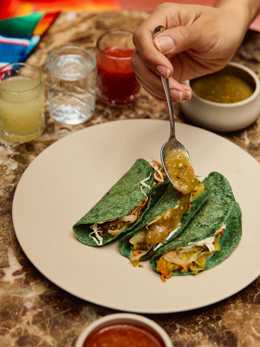 mano sirviendo salsa sobre quesadillas de tortilla verde