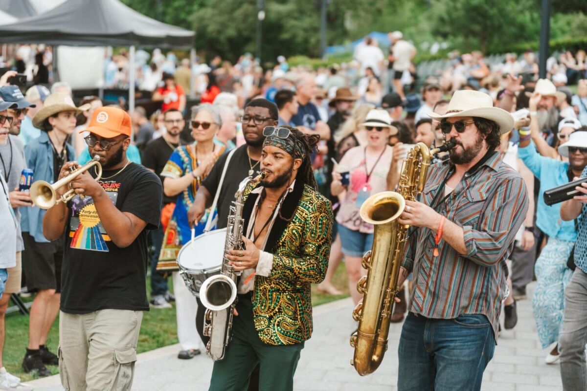 músicos tocando el saxofón entre la multitud