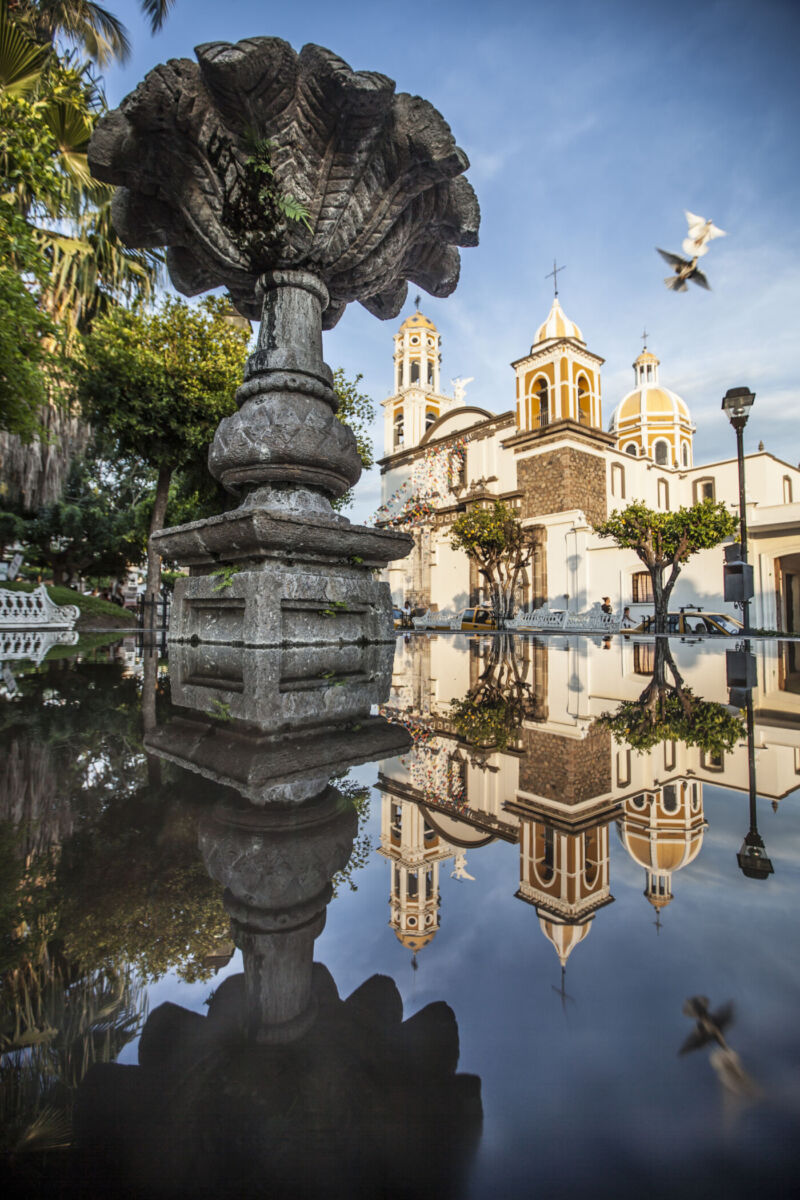 iglesia de comala reflejada en el agua de una fuente de cantera