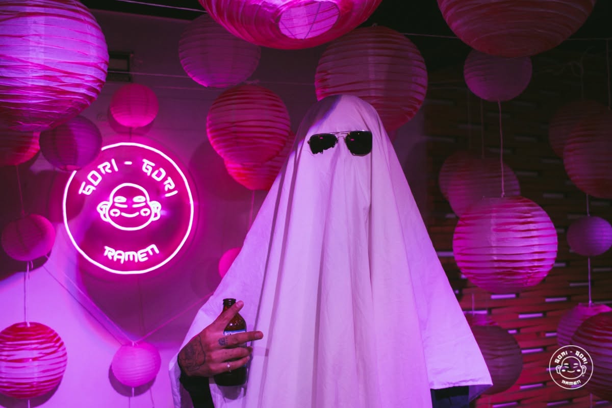 logo de gori gori con persona vestida de fantasma con lentes en un evento de halloween