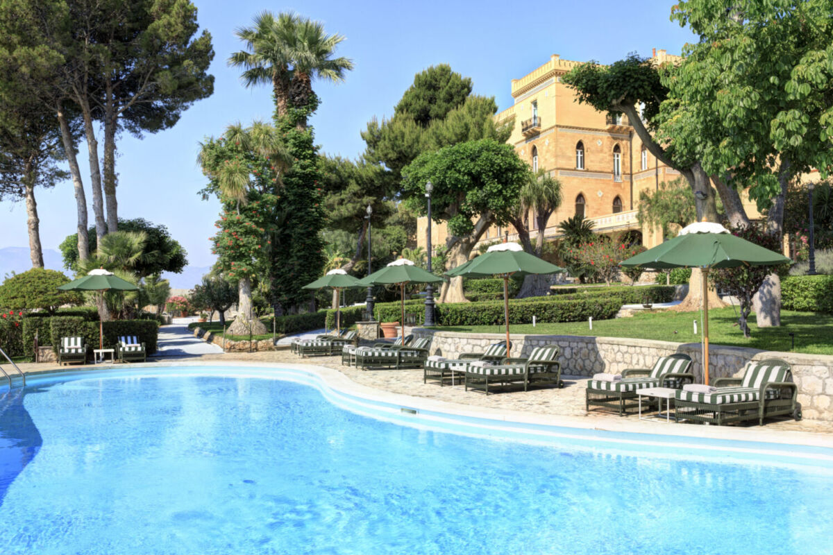 villa italiana con alberca al aire libre y camastros elegantes en un día soleado