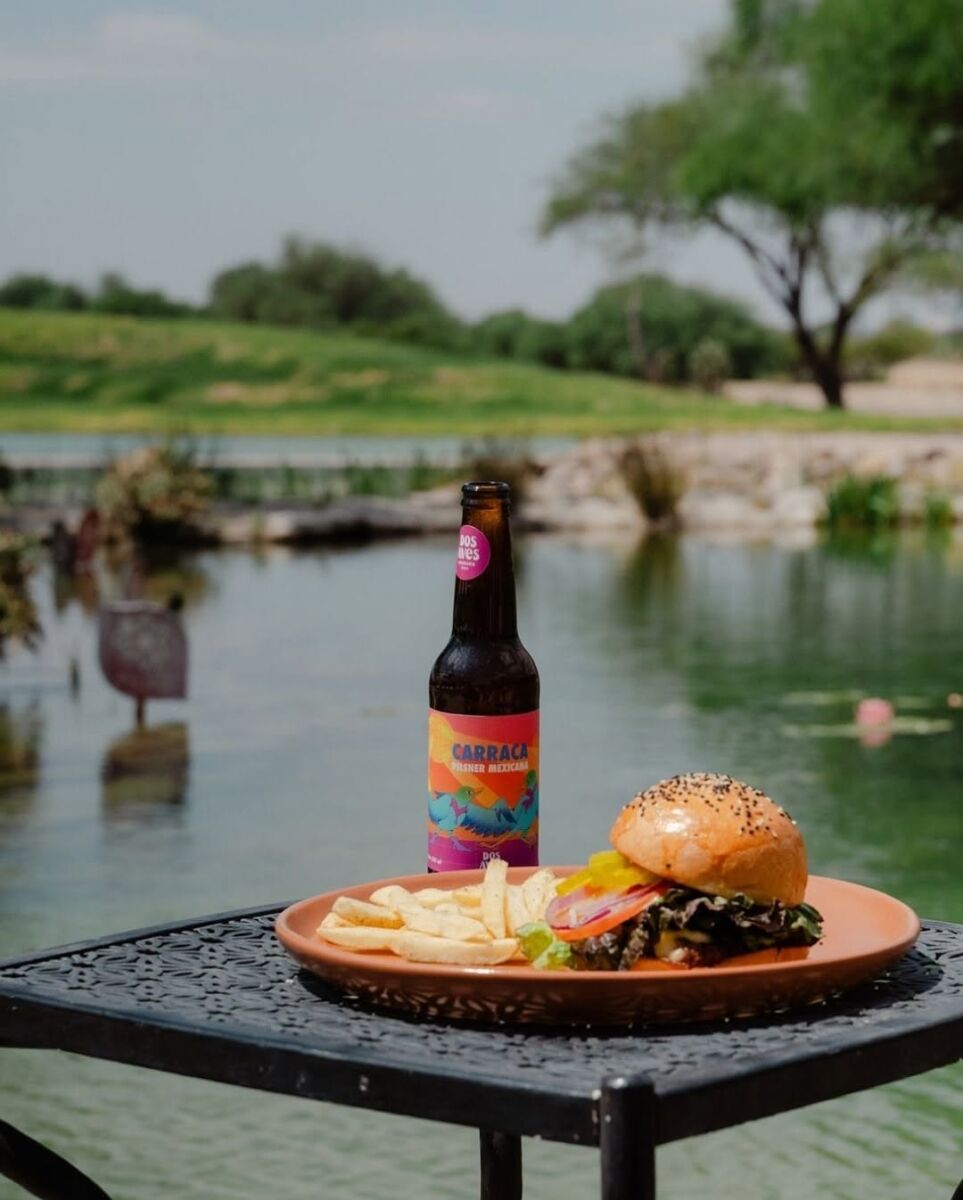 una hamburguesa con una cerveza artesanal frente al lago de la playita