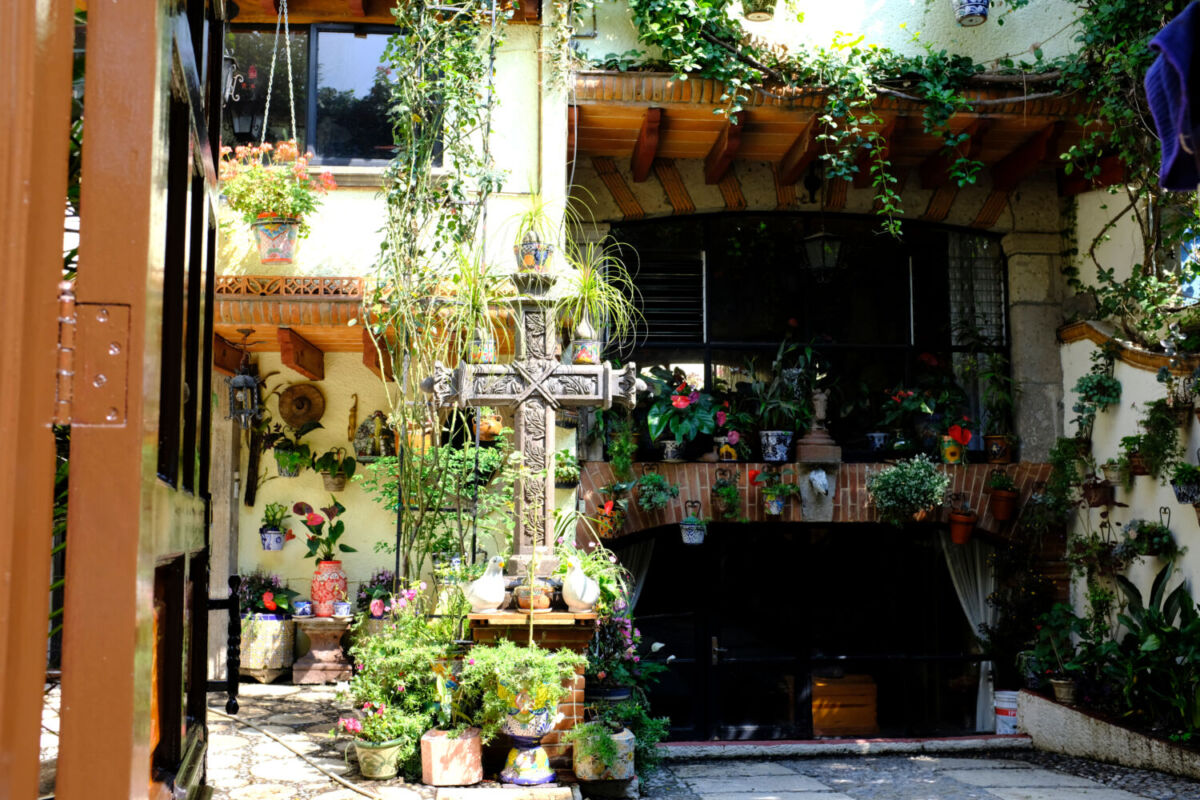 jardín con plantas, artesanias y una cruz de piedra labrada