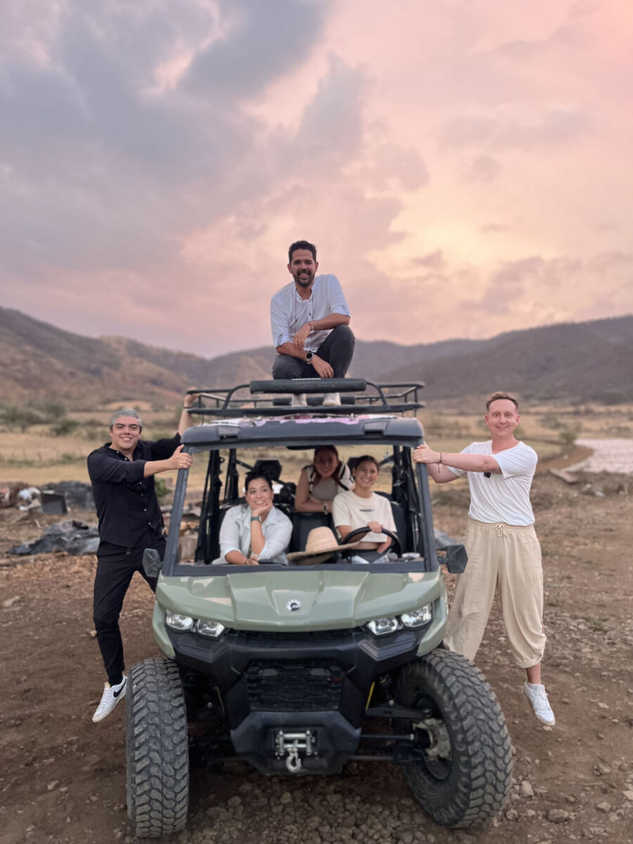 personas posando en un vehículo todo terreno al atardecer