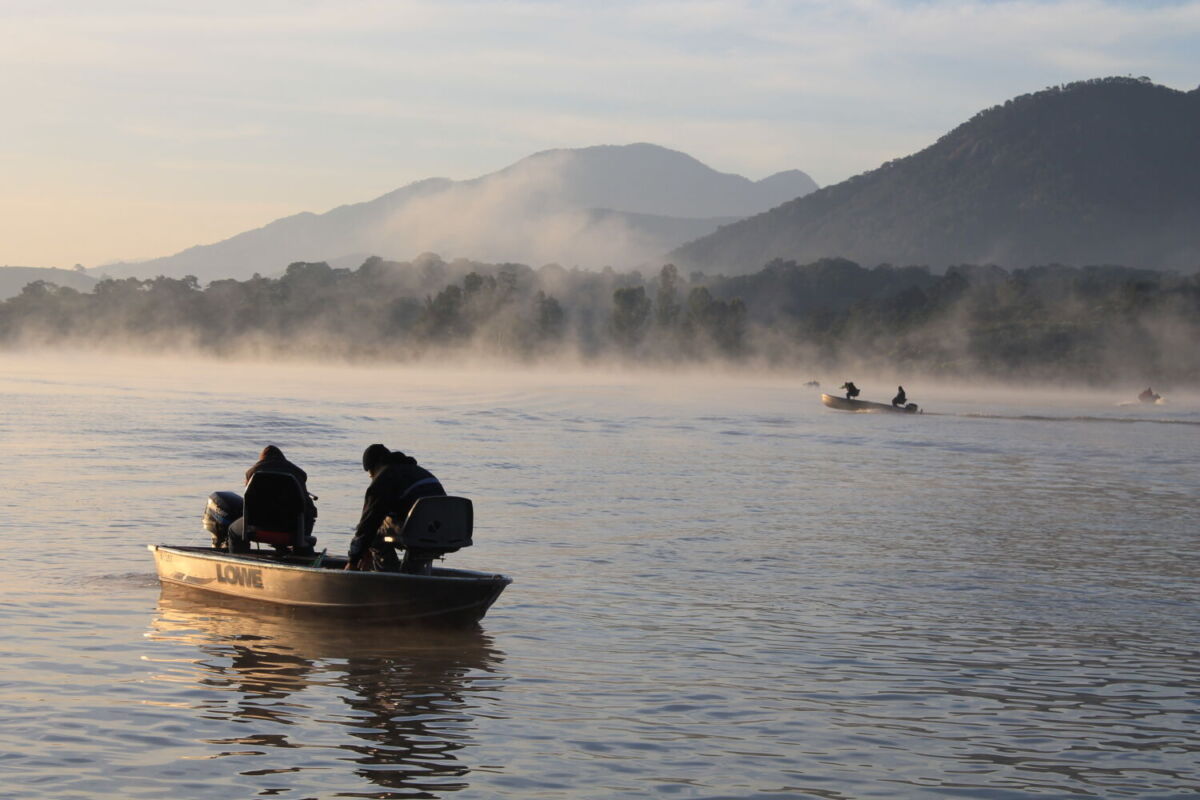 personas en lancha en una laguna con neblina y montañas al fondo