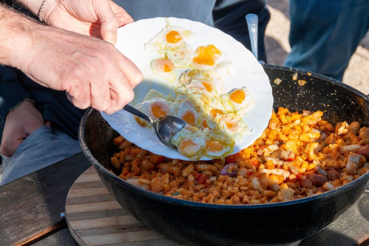 personas colocando en un plato migas españolas 