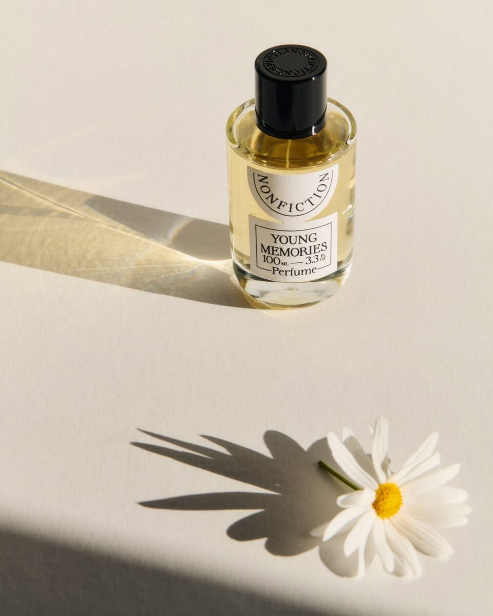 perfume de nonfiction en un fondo blanco con una margarita blanca