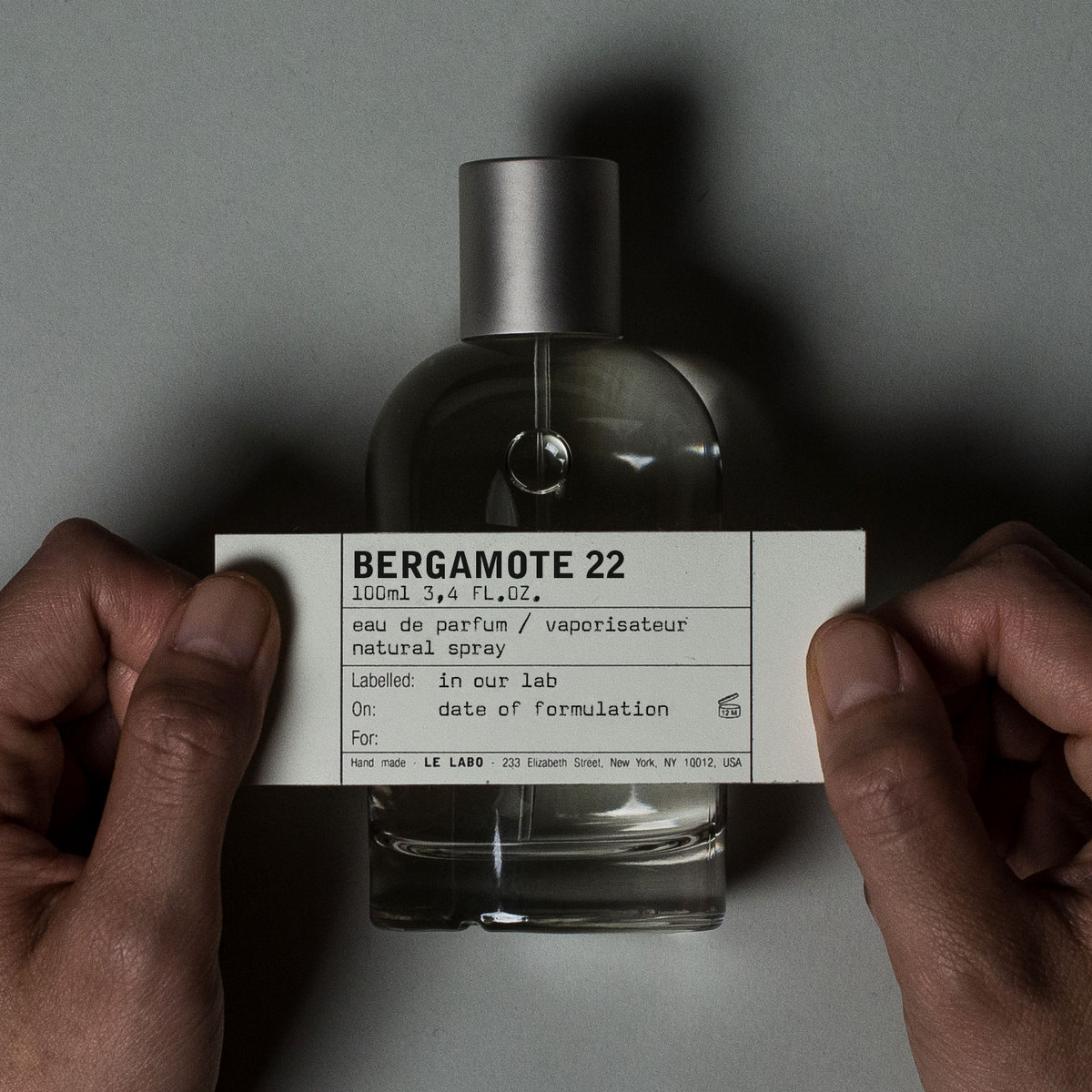 manos poniendo etiqueta de perfume lelabo