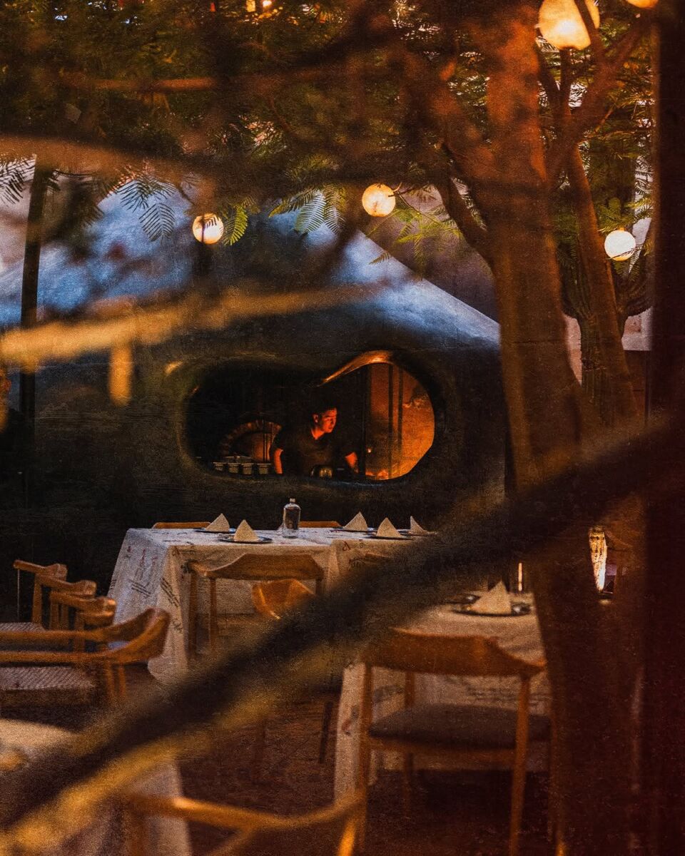 patio de un restaurante elegante por la noche, con luces colgando de un árbol