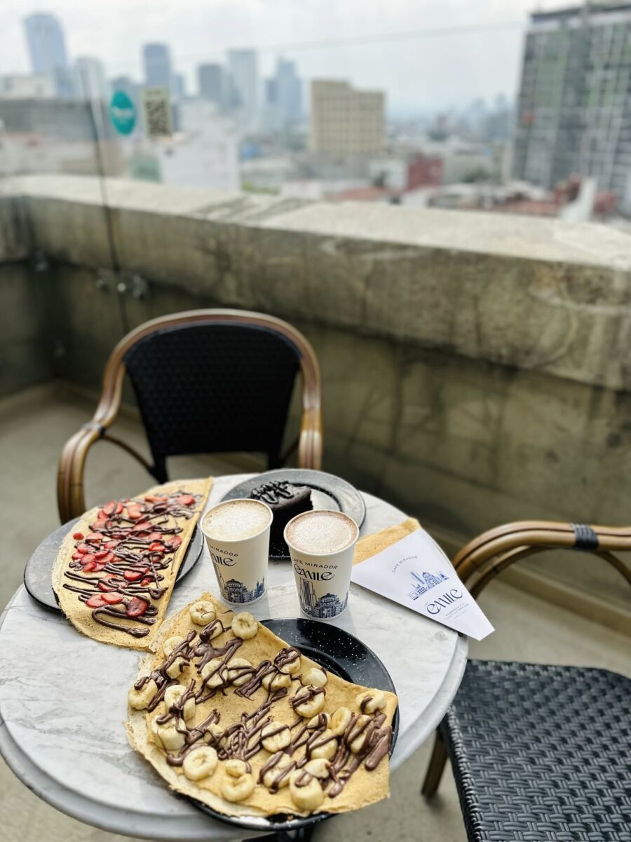 creapas y cafe sobre una mesa de cafetería con vista a la ciudad