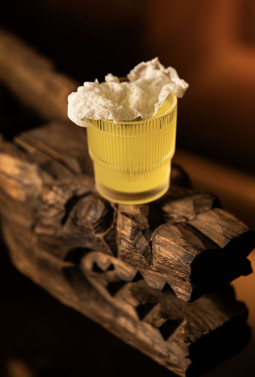Coctel amarillo con flor en un cocodrilo de madera