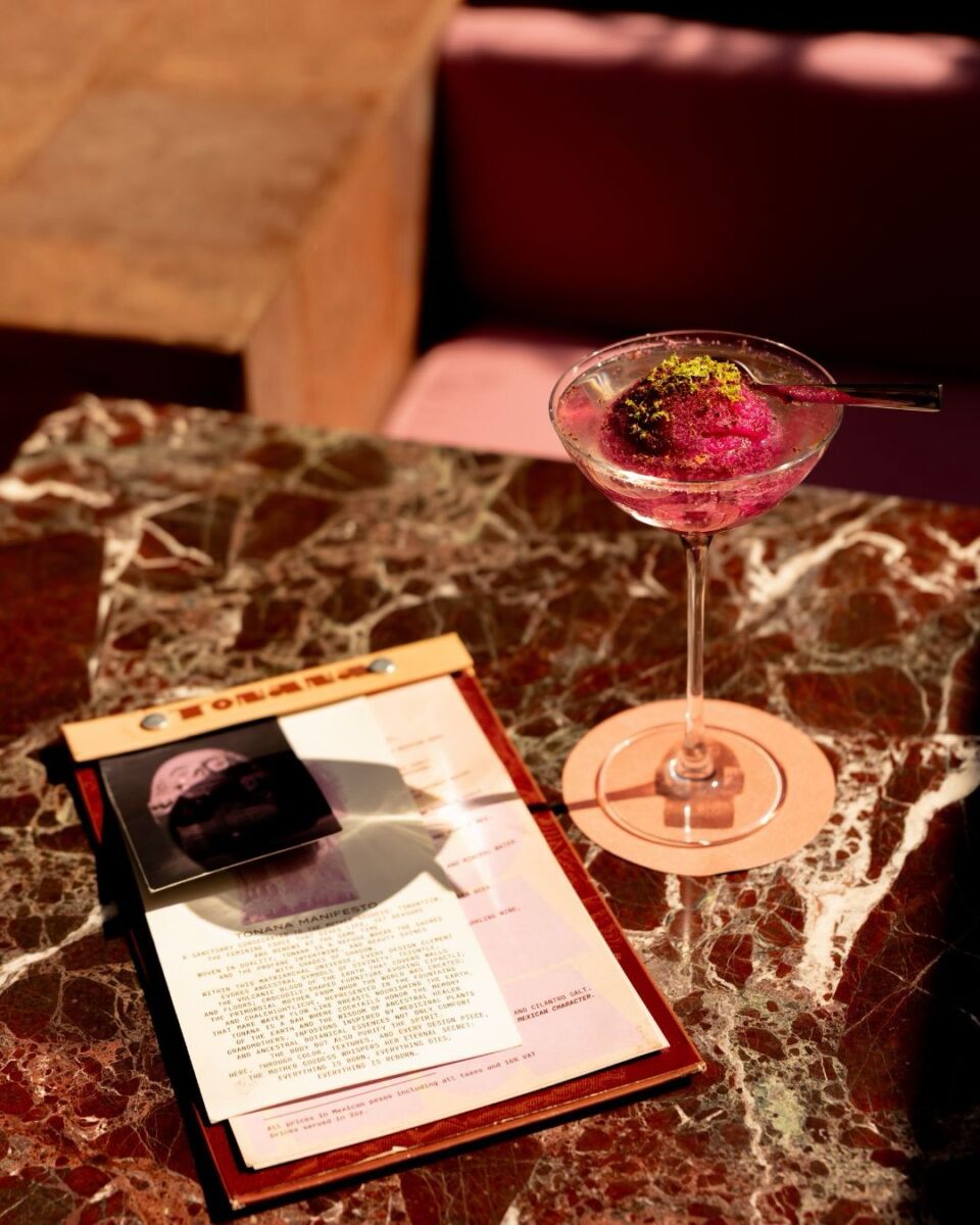 Coctel morado con un menú al lado en Tonana