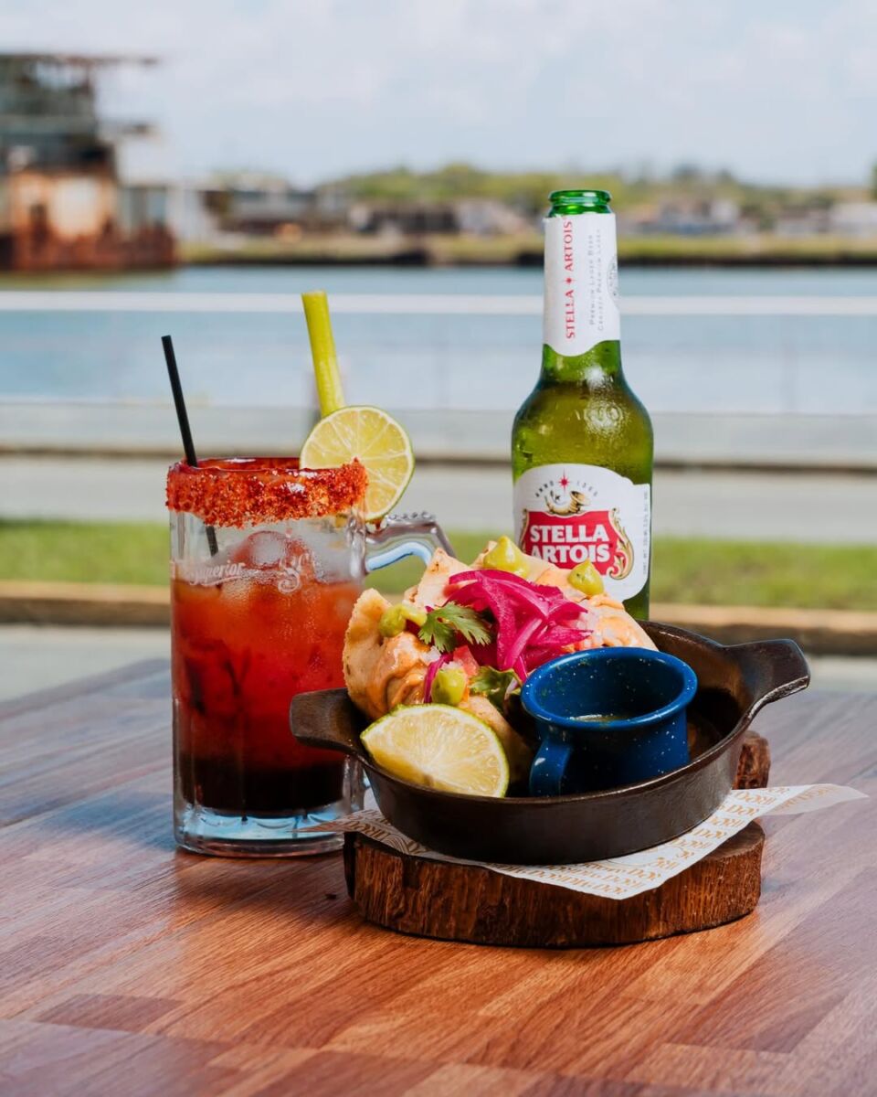 Foto de comida mexicana con cóctel y cerveza frente al puerto