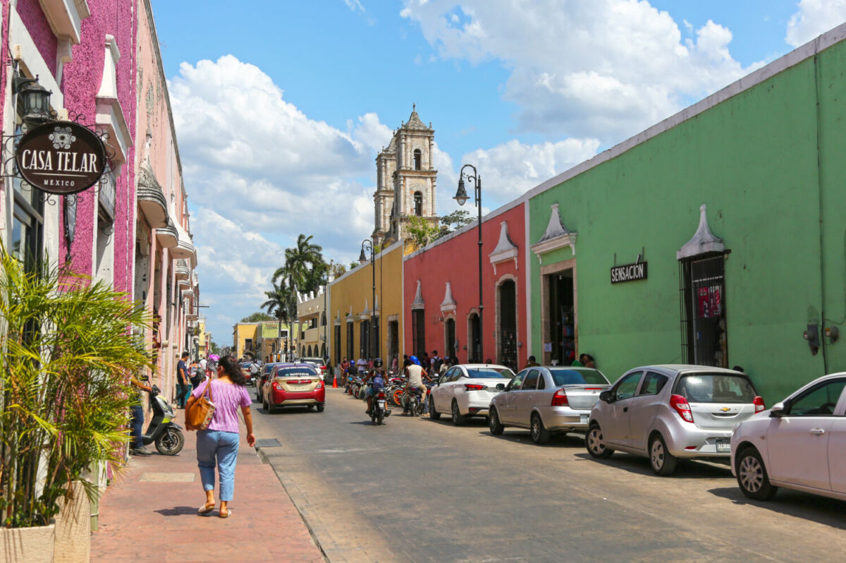 mujer caminado por una calle con casas coloridas en Valladolid, Yucatán 