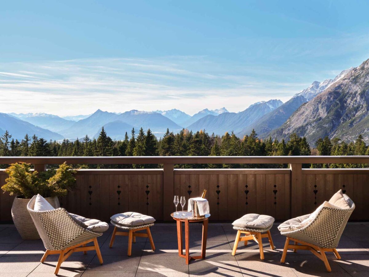 terraza con vistas a las montañas, con dos sillas y una mesa con copa de vino