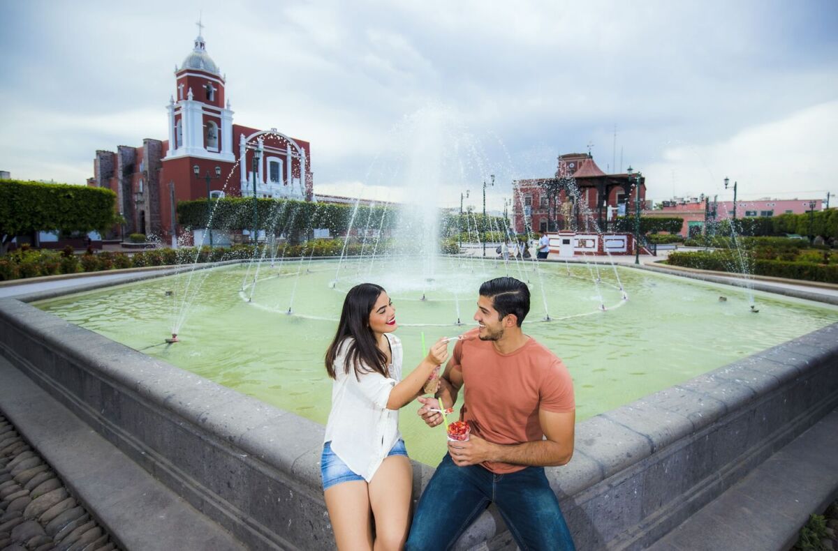 pareja comiendo fresas con crema frente a una fuente