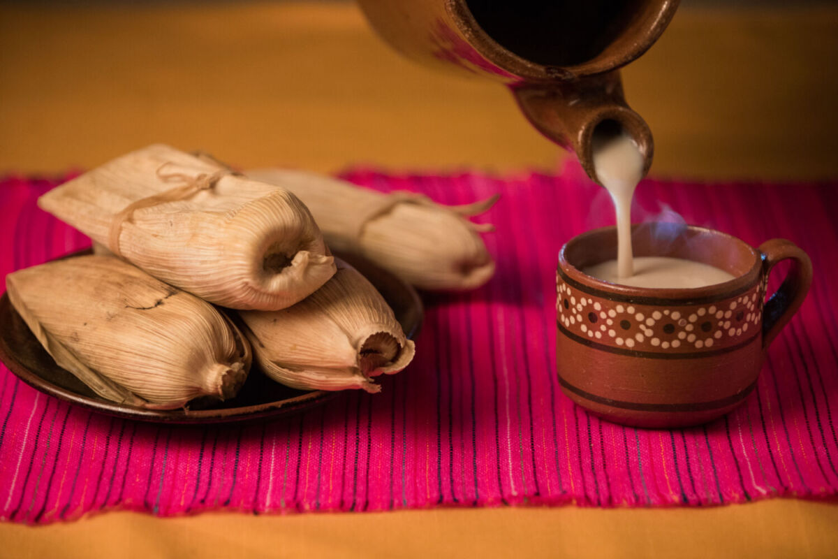 persona sirviendo atole y tamales 