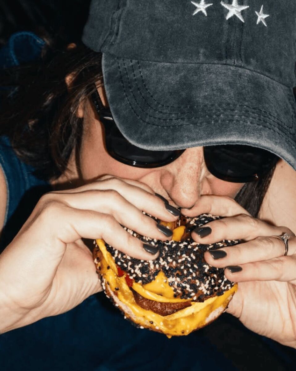 mujer con lentes oscuros mordiendo un bagel