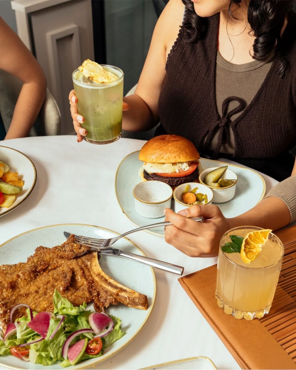 personas comiendo hamburguesas y milanesa en city market café