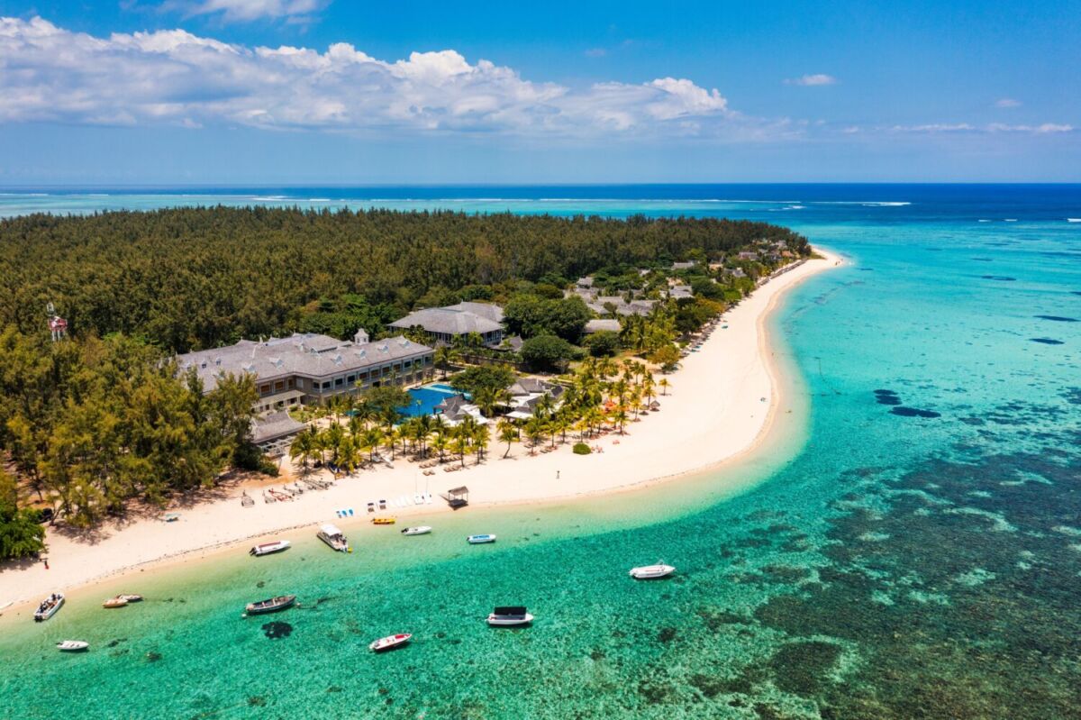 Vista aérea de un resort frente a laguna turquesa con arrecife de coral y lanchas ancladas en Mauricio