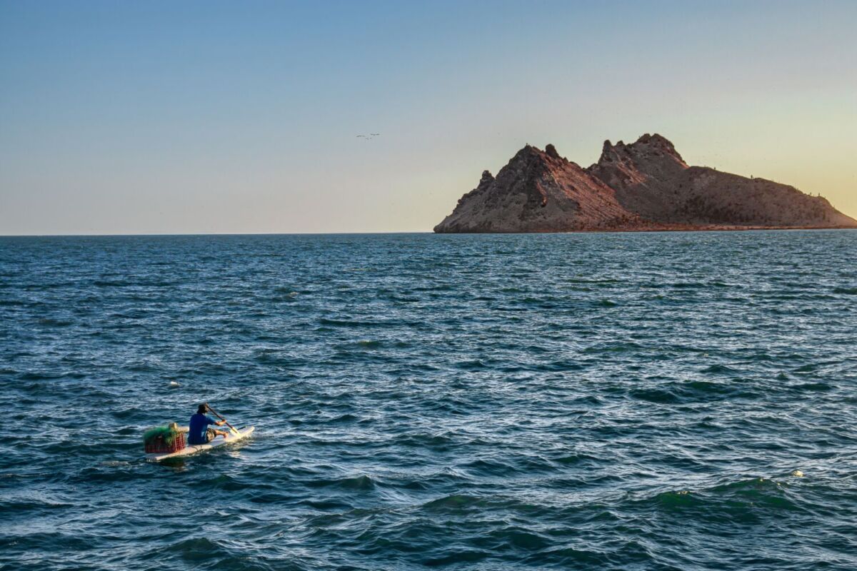 mar en la tarde con lanchero hacia rocas al fondo