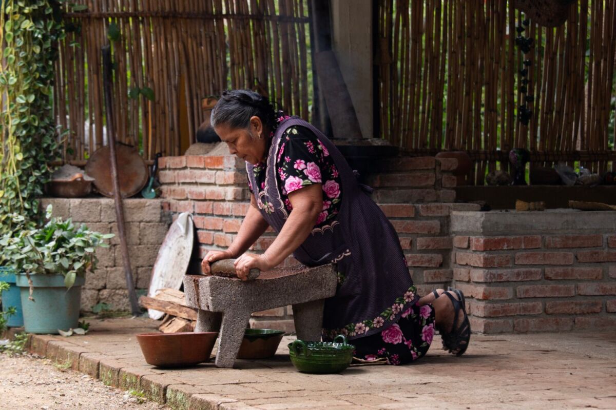 mujer haciendo masa en un metate