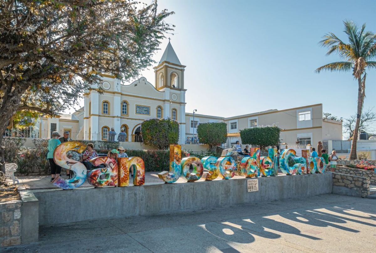 Letras monumentales de San José del Cabo frente a la misión colonial, con visitantes disfrutando la plaza principal