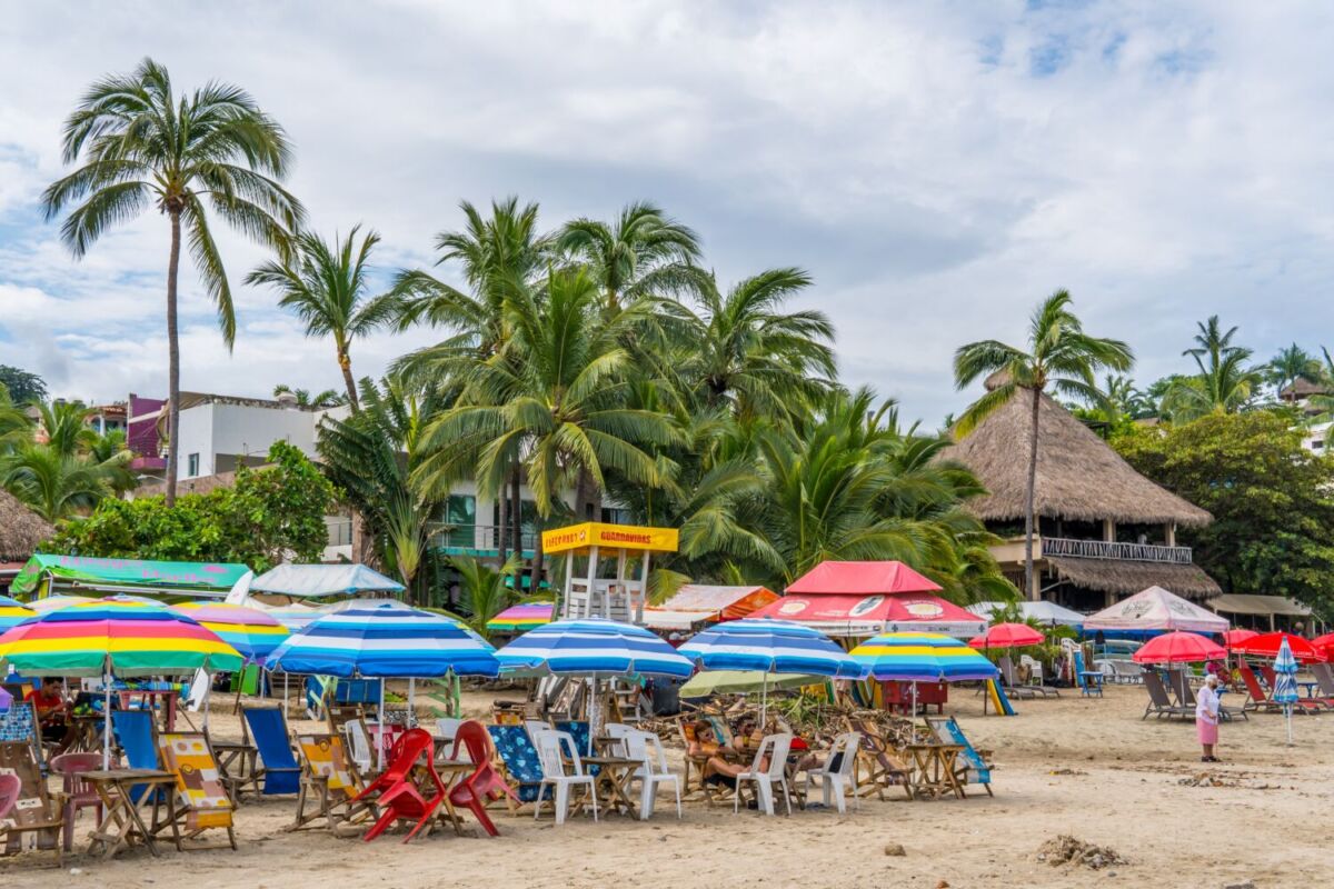 mesas, sillas y sombrillas sobre la arena, en una playa mexicana