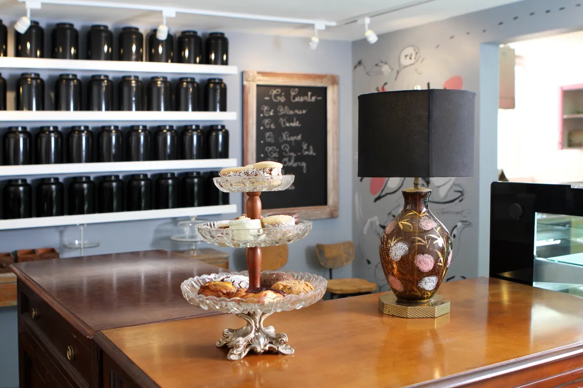 postres al frente en mesa de madera con repisas de infusiones diferentes