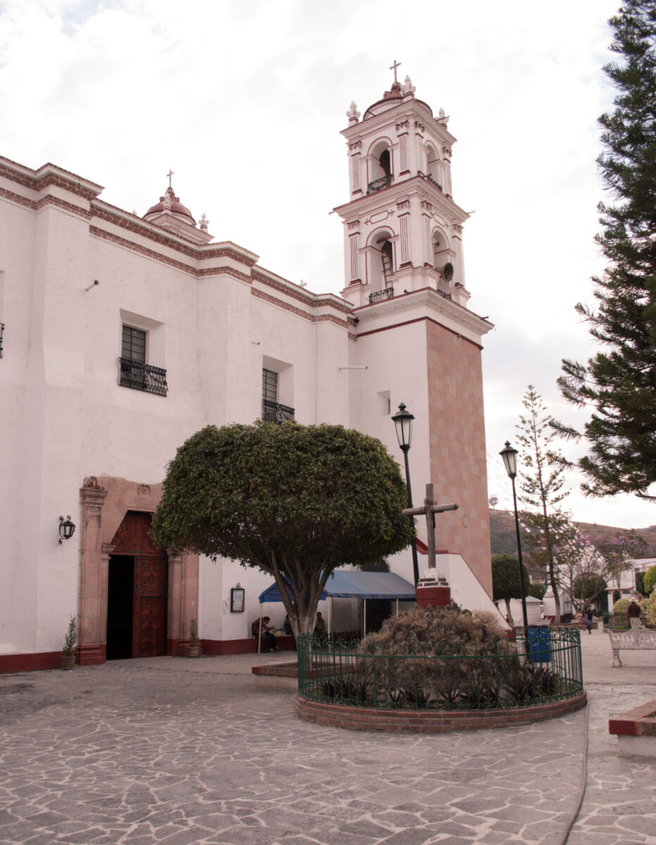 Iglesia colonial de cantera rosa con torre campanario y atrio arbolado en Tonatico, Estado de México