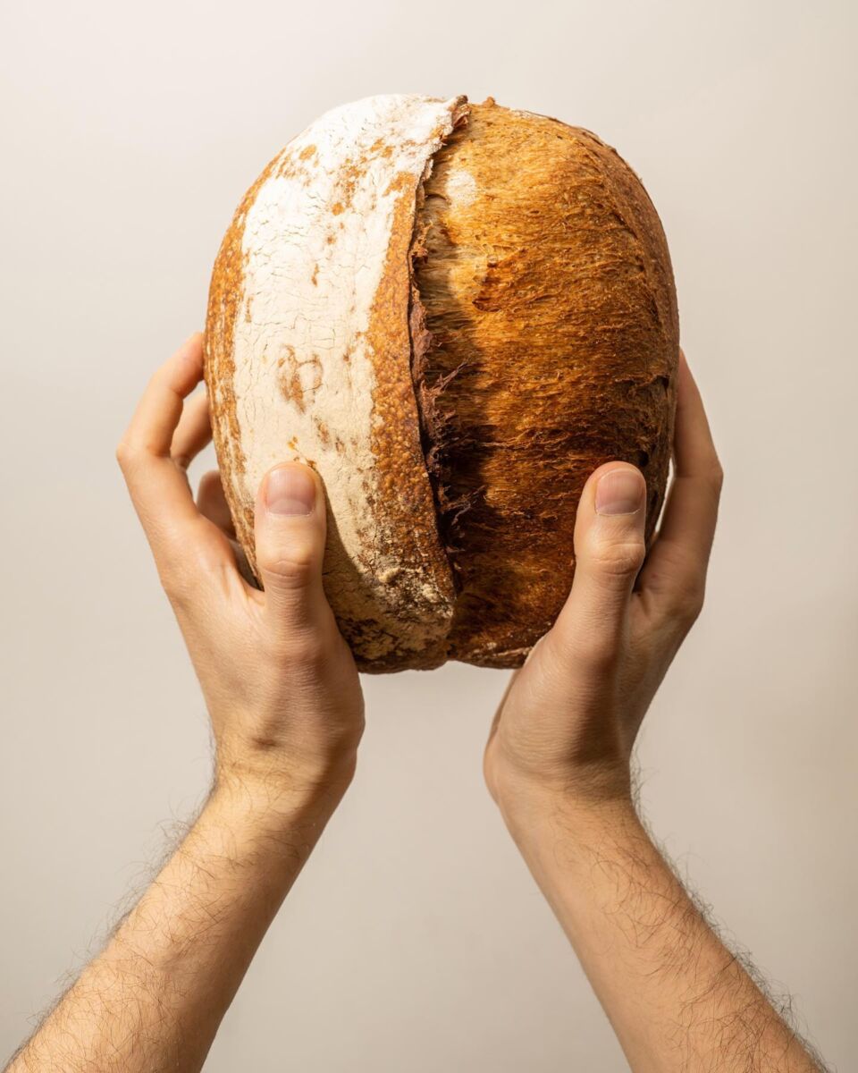 manos sosteniendo una hogaza de pan de masa madre