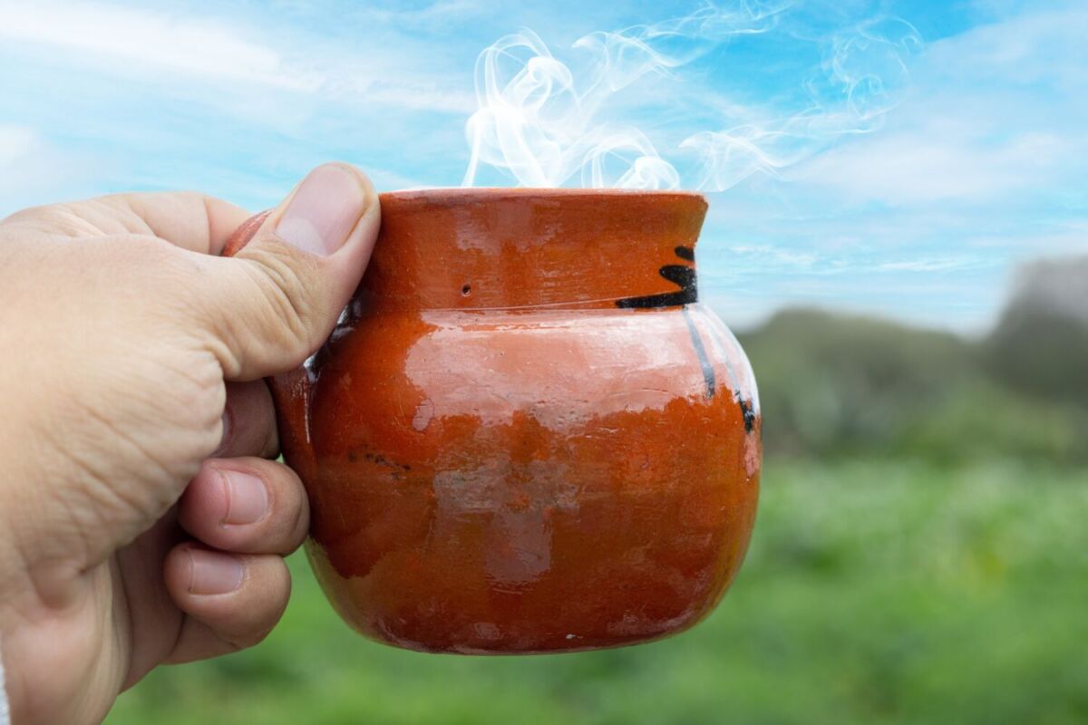 persona sosteniendo una taza de barro 