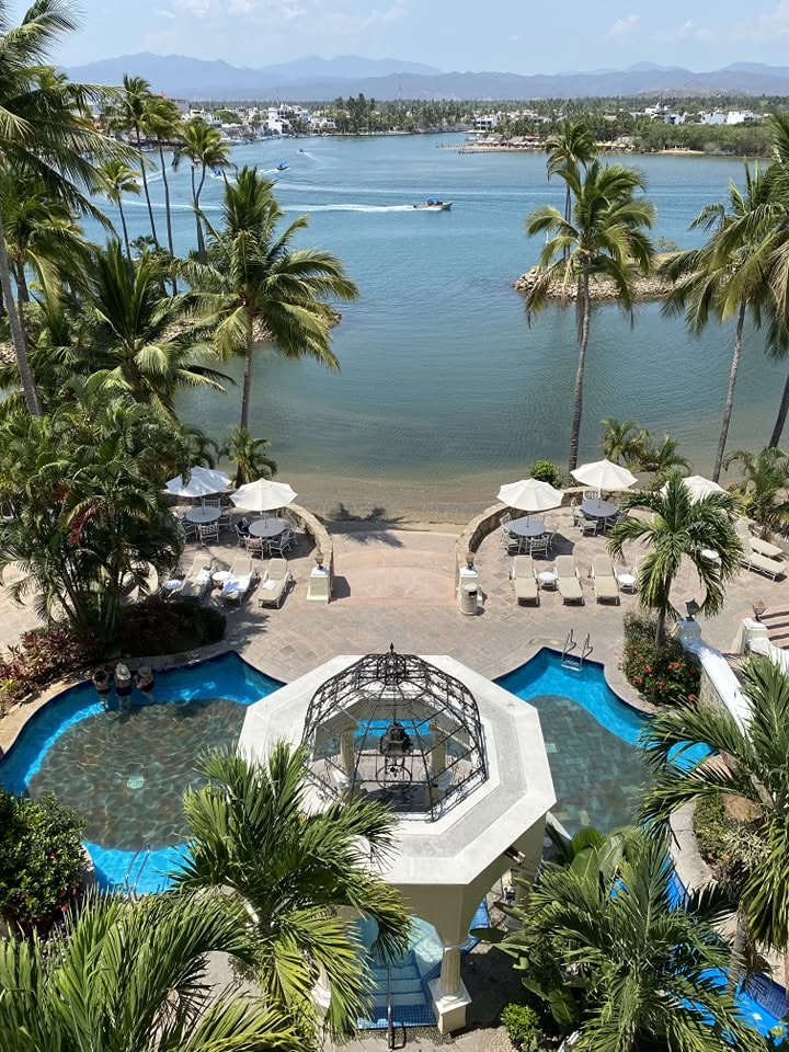 Albercas y kiosco del Grand Isla Navidad Resort con vista a la Laguna de Navidad y palmeras de la Costa Alegre