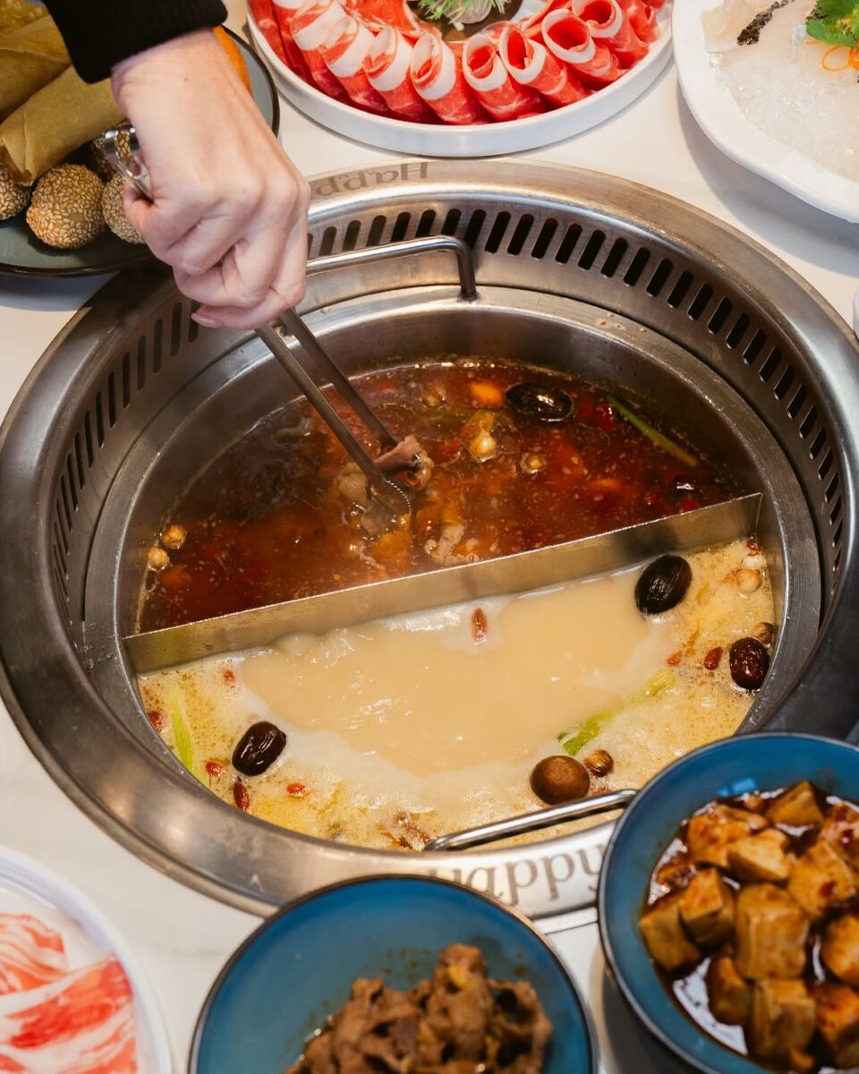 Una persona sumergiendo un pedazo de carne en hot pot