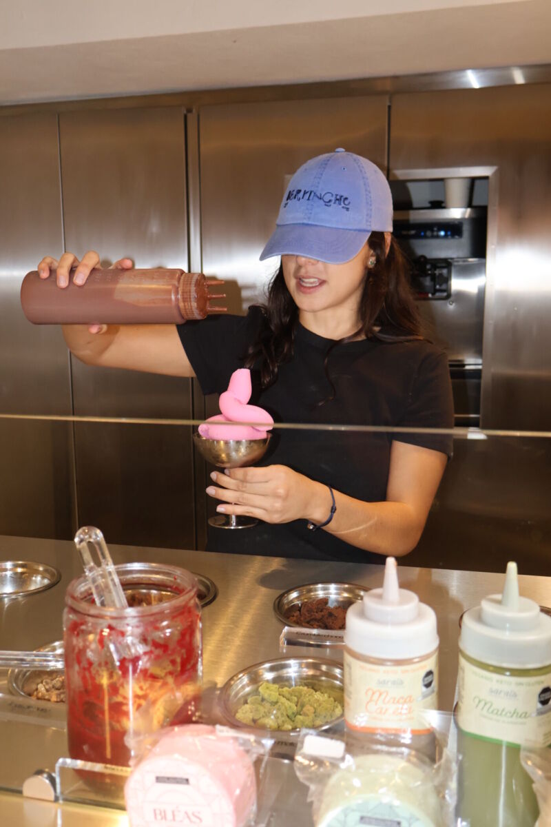 mujer poniendo chocolate sobre un helado de yogurt