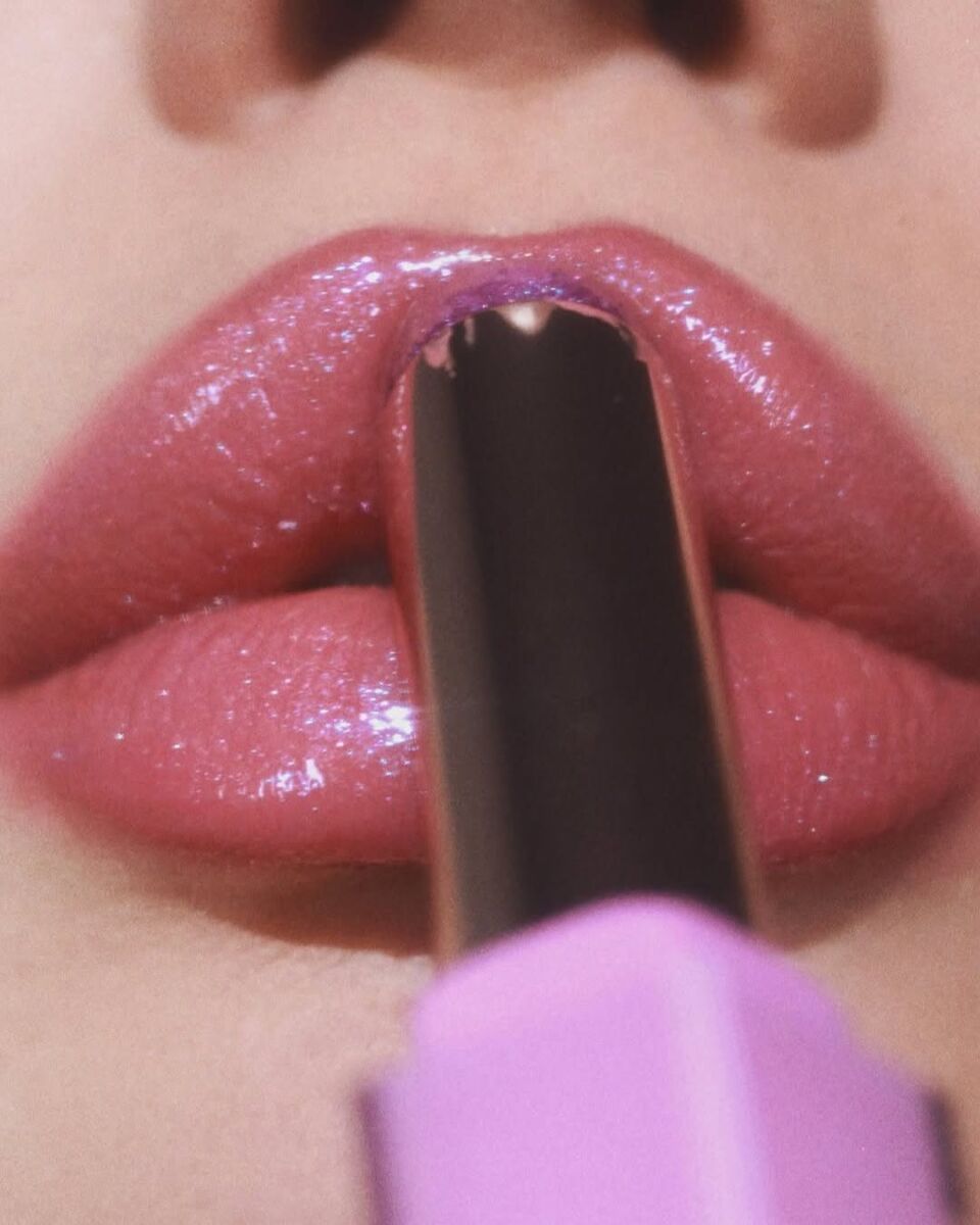 close up mujer aplicándose lip gloss en barra rosa