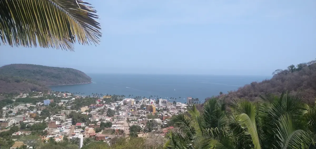 Pueblo rodeado de montaña y playas y vegetación tropical con aguas azul intenso 