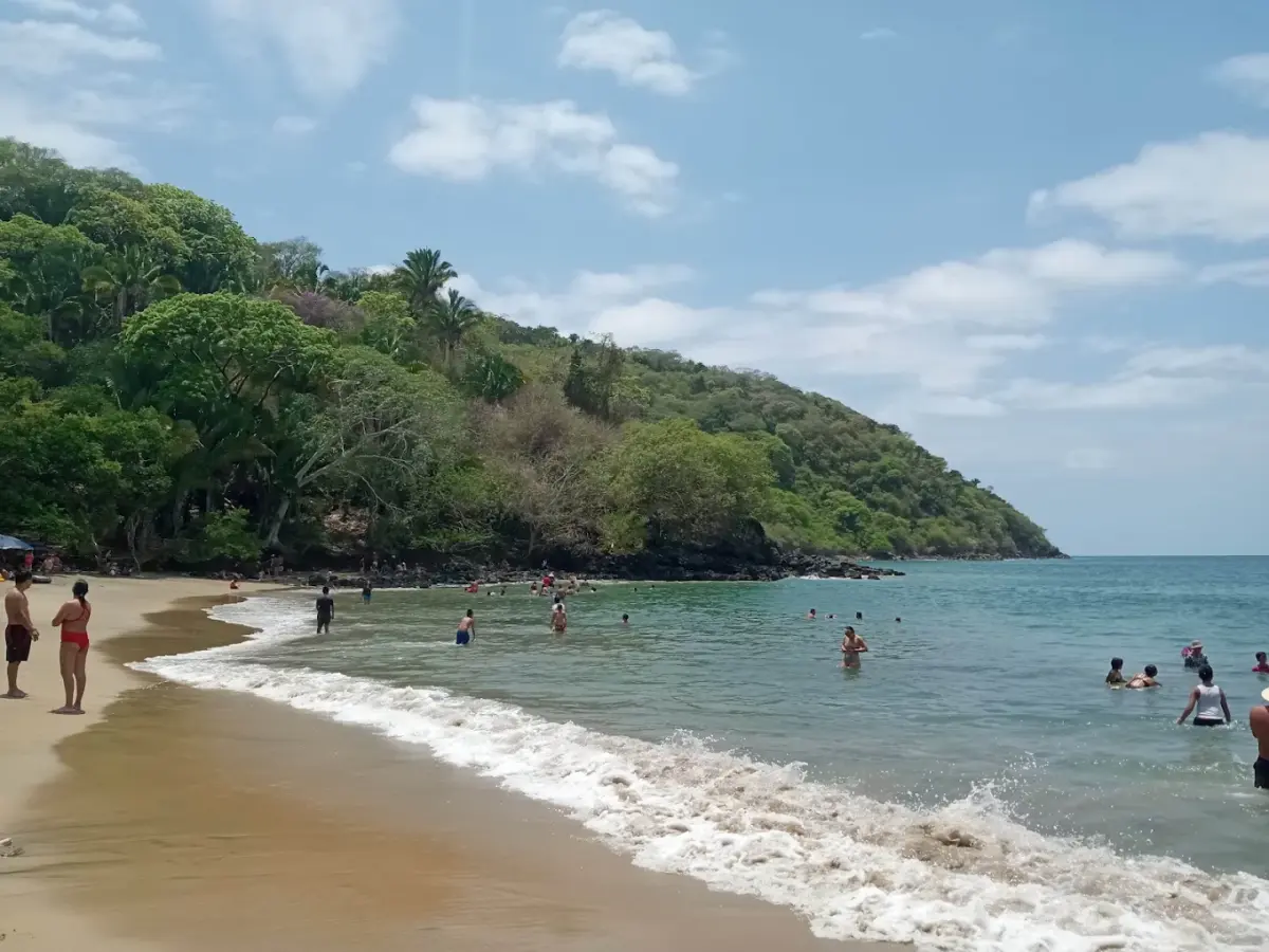 Bañistas en la playa de Los Ayala con el cerro cubierto de vegetación tropical al fondo, Riviera Nayarit