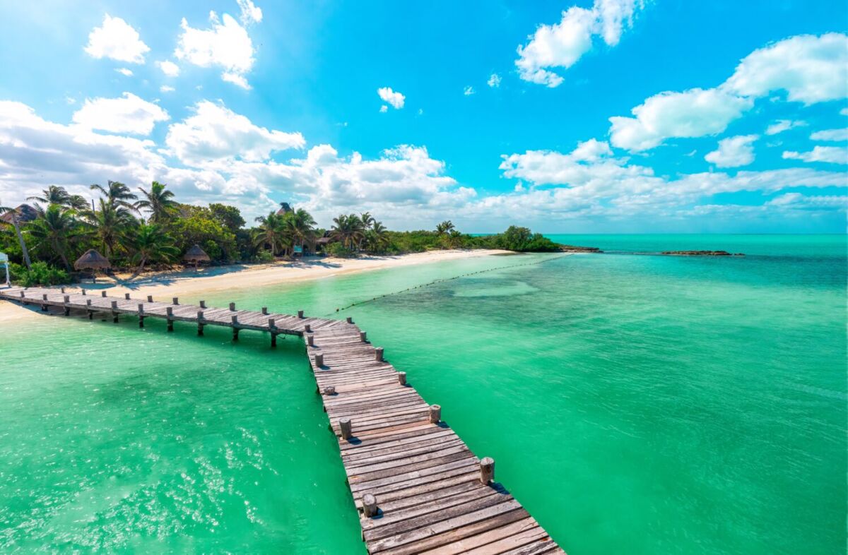 Playa de arena blanca casi virgen con palmeras y agua turquesa cristalina en la Riviera Maya