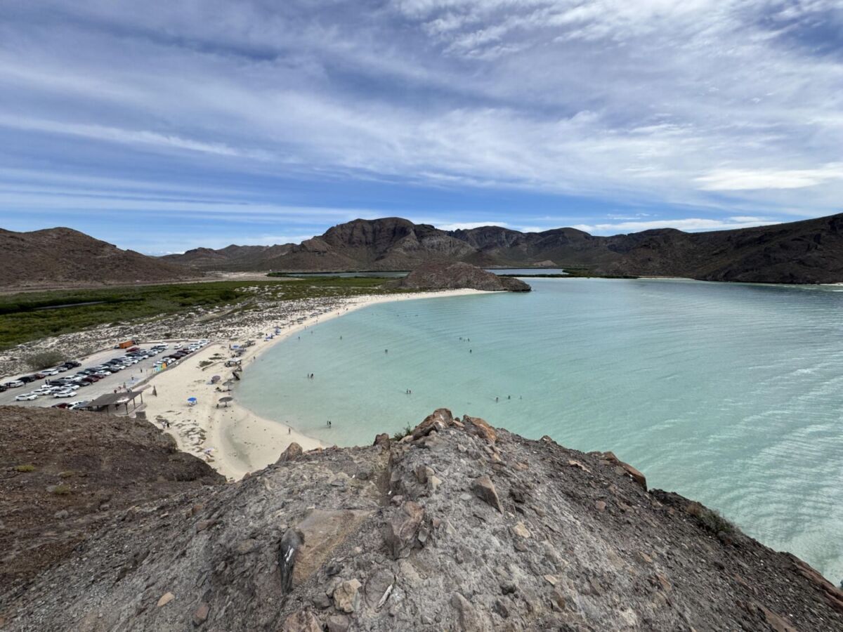 Vista panorámica de Playa Balandra con aguas turquesas poco profundas y estacionamiento lleno en La Paz, BCS