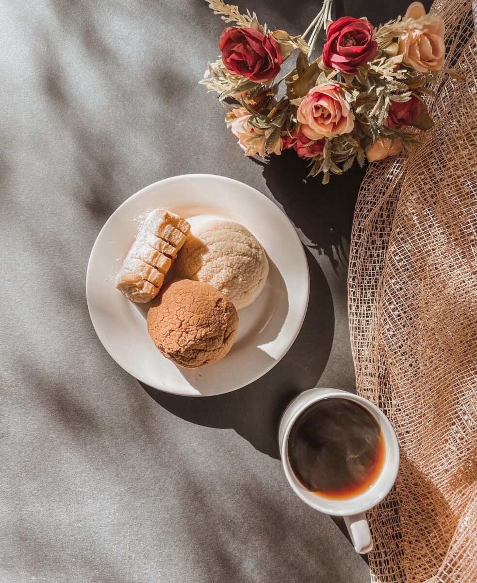 pan dulce y café sobre saban ablanca con flores y cesta