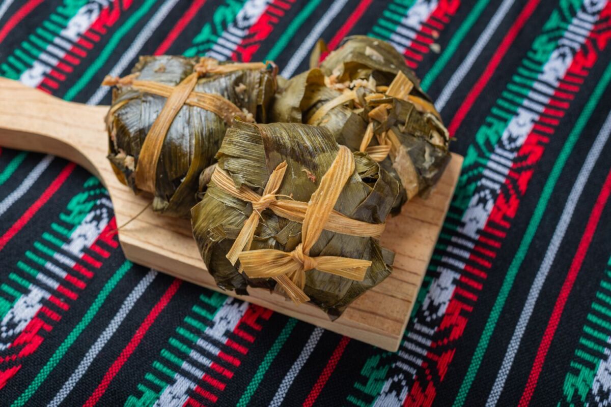 tamales de ceniza sobre plato de madera y mantel de tela de colores