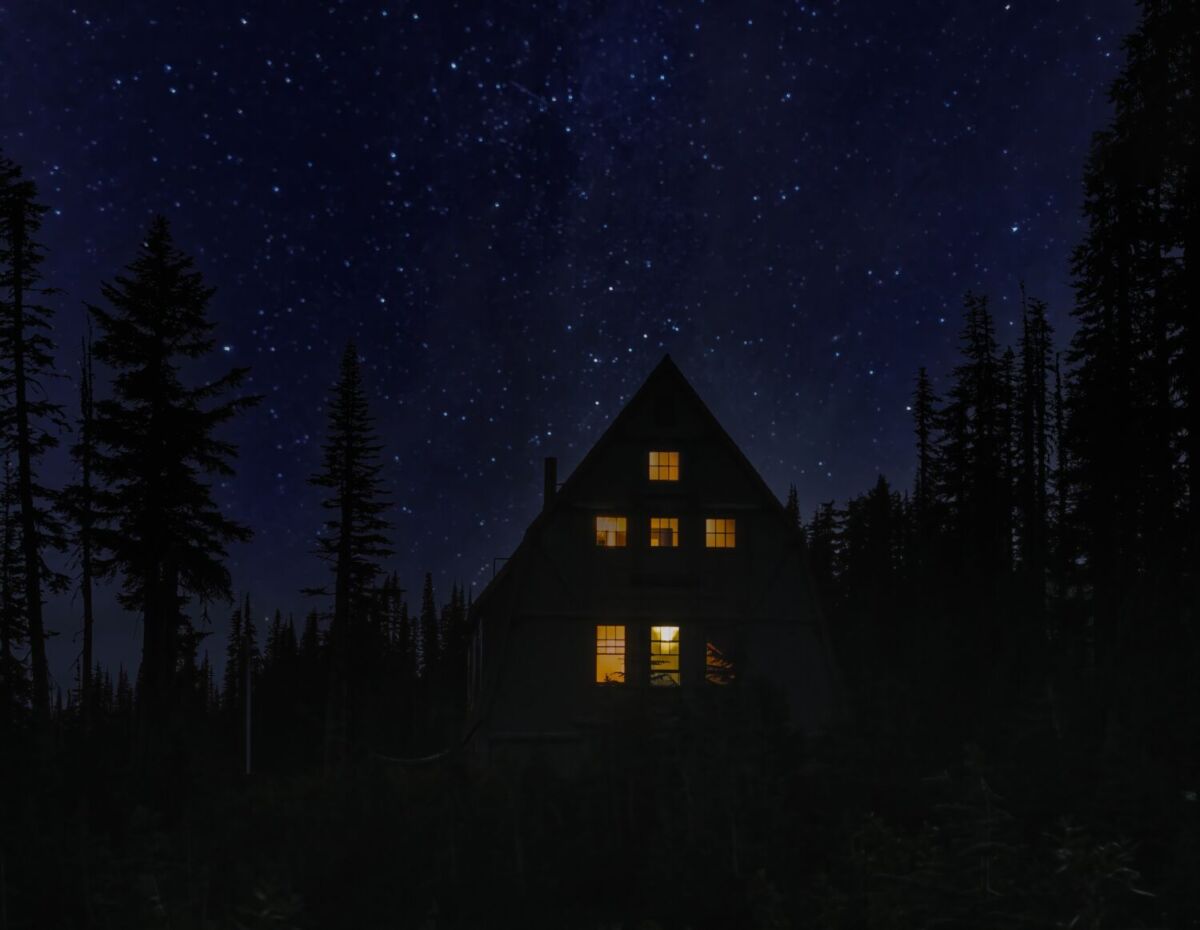 Casa de noche en bosque bajo las estrellas